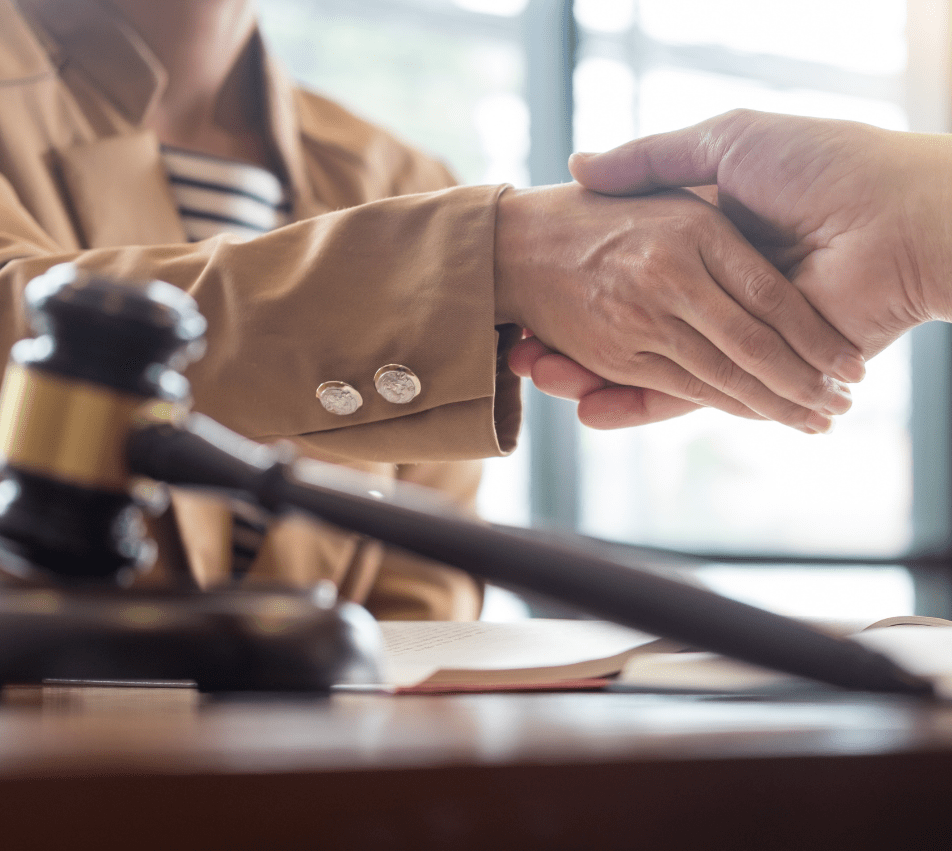 Client shaking hands with criminal defence lawyer Daryl Royer across a desk with a judge's legal gavel in the foreground.