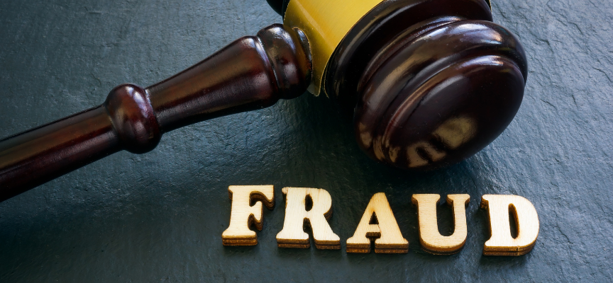 A close-up of a judge’s gavel resting next to the gold letters "FRAUD" on a dark background, symbolizing the legal process for financial fraud charges in Alberta and Edmonton courts.