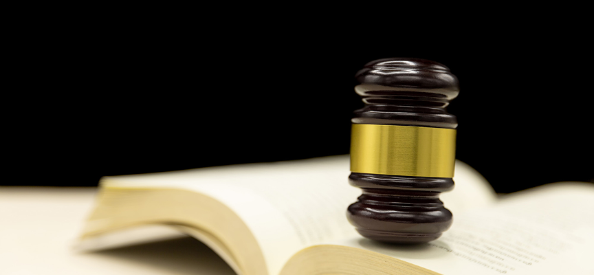 A wooden judge's gavel with a brass band resting on top of an open law book, representing defense counsel during pre-trial and bail hearings. A wooden judge's gavel with a brass band resting on top of an open law book, representing defense counsel during pre-trial and bail hearings.
